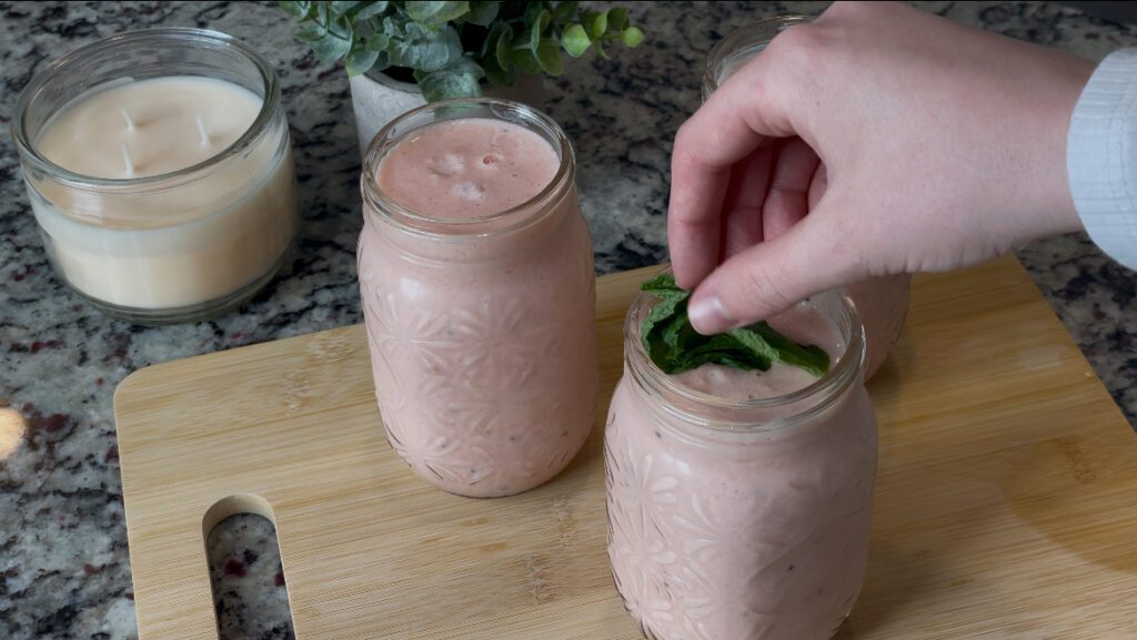 Garnishing HarvesTime Watermelon Kiwi smoothie in jar with mint leaves